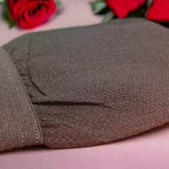 Close-up of textured Moroccan hammam glove with woven fibers against spa backdrop, showcasing exfoliating surface detail