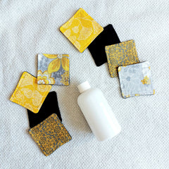 Makeup remover pads with floral patterns, yellow, gray, and black fabric, with a white bottle