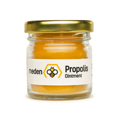 Golden propolis balm in a sleek amber glass jar with minimalist black lid, showcasing natural skincare texture