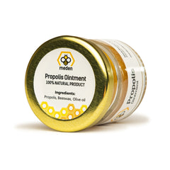 Close-up of golden propolis balm with rich, creamy texture in a sleek amber jar, showcasing natural skincare luxury