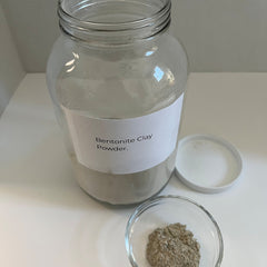Bentonite clay powder in glass jar with white label, small bowl of clay and white lid