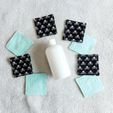 Makeup remover pads, black skull print fabric, and light blue fabric pads on a white towel