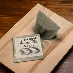 Sea clay soap bar with gray color and wrapped in plastic on a wooden board