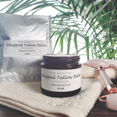 Hand scooping whipped tallow balm from a minimalist glass jar onto fingertips