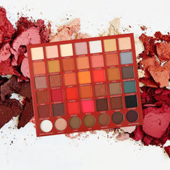 Eyeshadow palette with red, orange, and neutral shades, in a rectangular palette, with names on each color