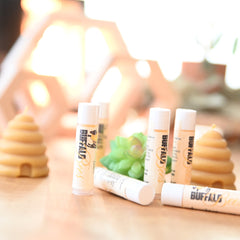 Lip balm tubes with white and tan labels, "Buffalo Bees" branding, and a lemon flavor label