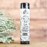 Sunscreen lip balm tube with white label, black text, and One Blessed Acre Farm branding