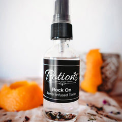 Toner bottle with black label, clear glass, and black spray top, by Potion's brand
