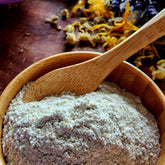 Facial cleanser powder in a wooden bowl with a wooden spoon, light beige color