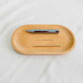 Acupuncture tray with silver teishin, gold needle, and wooden oval tray on white fabric