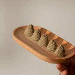 Incense cones, textured green, wooden tray, held by hand