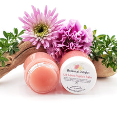 Lip balm jars with pink balm and white label, Botanical Delights brand visible, with flowers in background