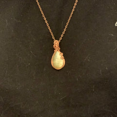 Side view of copper wire pendant with shimmering yellow mica stone in natural light