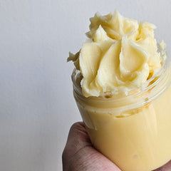 Hand scooping rich golden argan butter from a jar to apply on dry skin