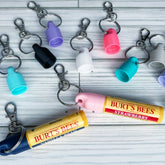 Keychain cap accessories with various colored plastic caps and metal key rings, Burt's Bees lip balm shown