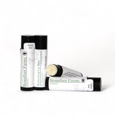Lip balm tubes with black caps and white labels, Stonefoot Farms branding visible, unflavored option shown