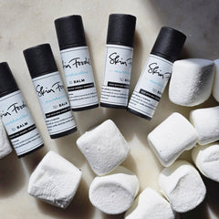 Lip balm tubes with black caps and white labels, next to white marshmallows, Skin Foodie brand