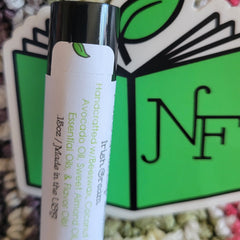 Lip balm tube with white label, black cap, and green leaf logo, with brand name visible