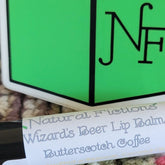 Lip balm with white label, green logo, and Natural Fictions text
