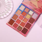 Eyeshadow palette with multiple colors, glitter, and pink packaging