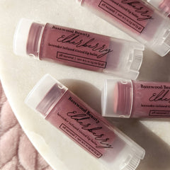 Lip balm tubes with lavender tinted color and white caps, Basswood Beauty brand visible