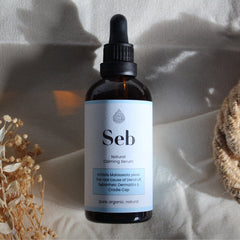 Close-up of amber glass serum bottle with dropper, showcasing golden sebum-calming liquid texture against natural light