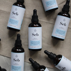 Hand applying translucent sebum-calming serum onto glowing skin with fingertips