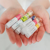 Natural lip balms in white tubes with fruit illustrations and Naturacare brand name, held in open hands