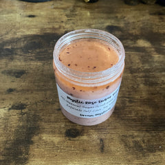 Sugar scrub jar with pink and orange contents, clear plastic container, and white label with text visible