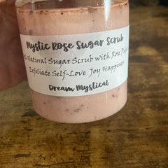 Sugar scrub in a pink jar with white label, "Mystic Rose" text, on wooden surface