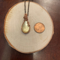 Close-up of copper wire pendant with shimmering yellow mica stone in natural light
