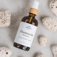 Side view of frosted glass toner bottle with rose and lavender botanical design, showcasing spray nozzle