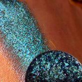 Eye shadow swatch with blue, green, and purple glitter on skin, Azuli eye makeup