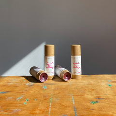 Lip therapy tubes in brown cardboard with white labels and red text on wooden surface