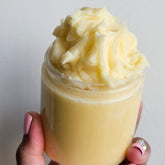 Golden glass jar of cold-pressed argan butter with minimalist white label and rich creamy texture