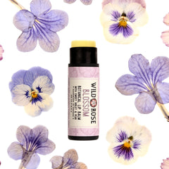 Lip balm with black tube, yellow balm, and Wild Rose Blossom label with flowers