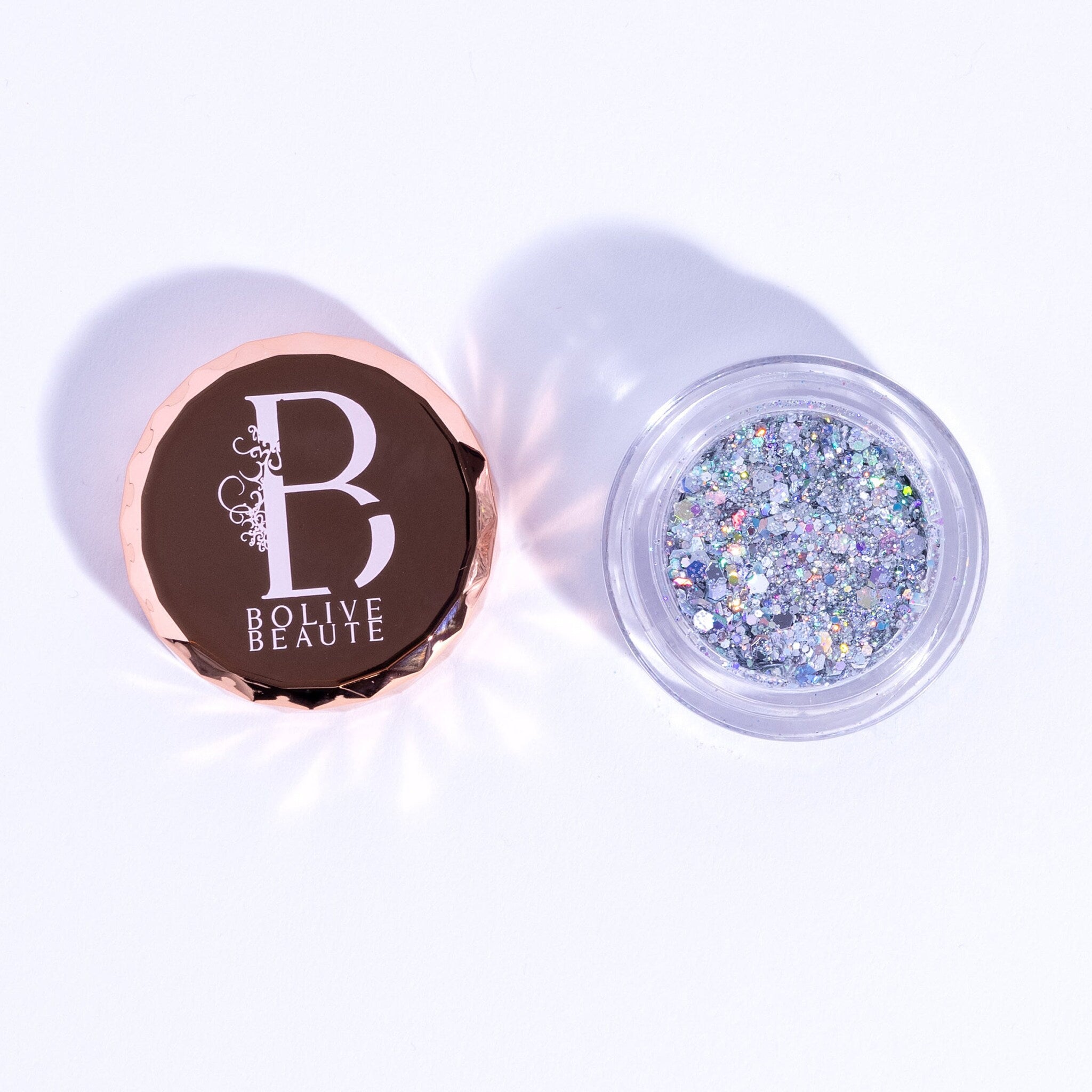 Close-up of holographic silver glitter eyeshadow in compact with reflective rainbow sheen