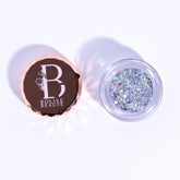 Close-up of holographic silver glitter eyeshadow in compact with reflective rainbow sheen