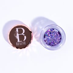 Close-up of holographic lavender glitter eyeshadow in a round compact with reflective purple packaging