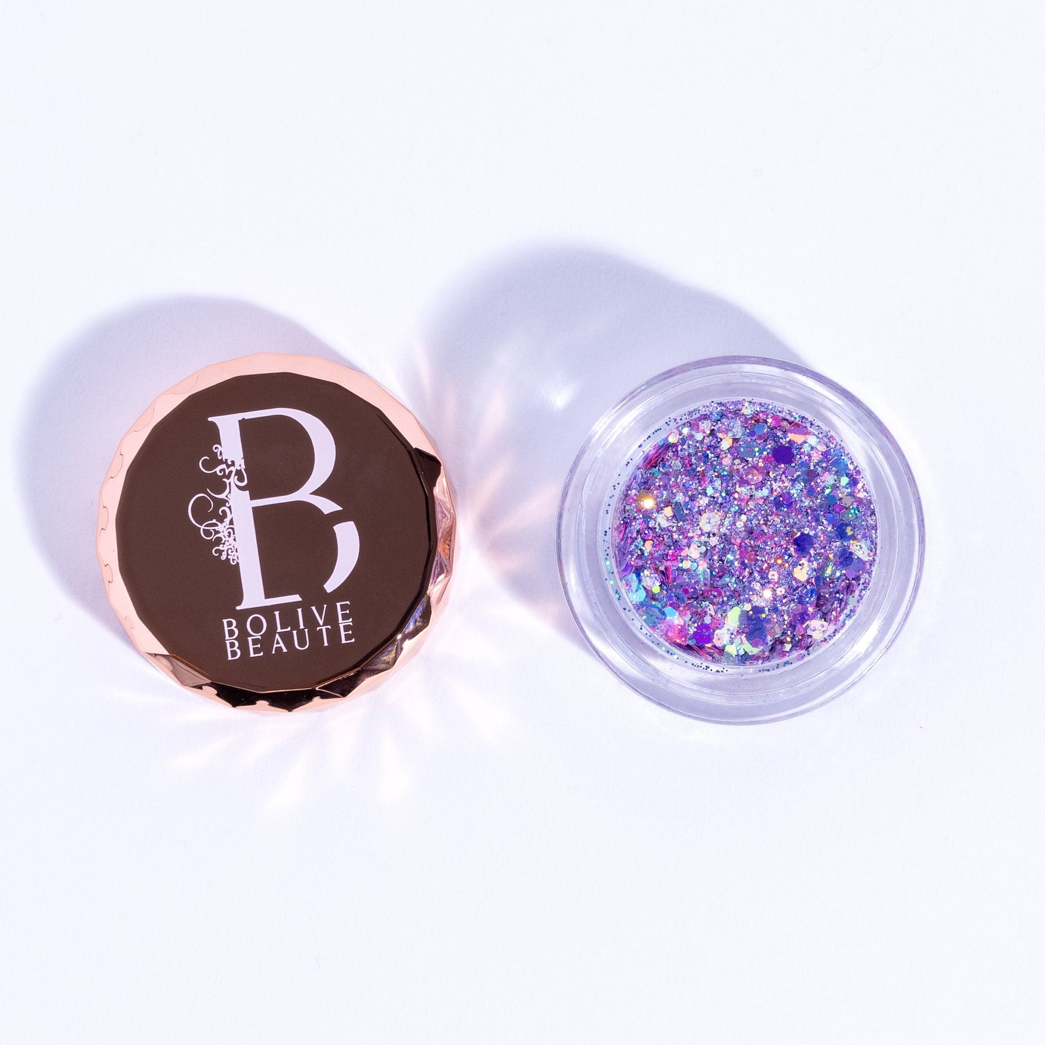 Glitter eyeshadow with iridescent purple and lavender colors in a clear jar, Bolive Beaute brand visible
