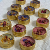 Lip balms in gold tins with various colors and dried flower toppings