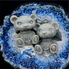 Gray teddy bear figurines with textured detail, resting on a blue and white crystal geode