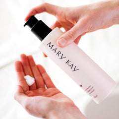 Lotion bottle with black pump and Mary Kay text, dispensing white lotion onto hand