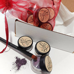 Eye shadow pots with black lids, purple powder, and Little Stuff4u branding, with a brush