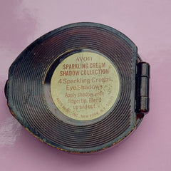 Eye shadow compact, black metal, ridged pattern, with Avon label on pink background
