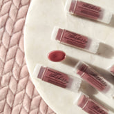 Lip balms, elderberry tinted, clear tubes, Basswood Beauty branding visible