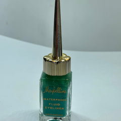 Close-up of vintage green eyeliner in glass bottle with golden spire lid, showcasing the fluid texture and retro design.