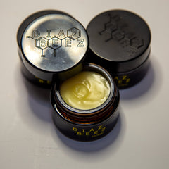 Ointment jars, black and silver lids with brand name, yellow cream visible inside jar