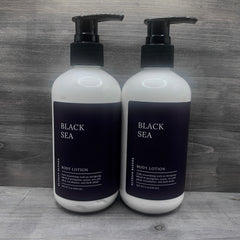 Body lotion bottles, white and black with pump, "BLACK SEA" text visible, by Elysian Blends