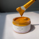 Turmeric exfoliating mask in jar with yellow brush, "Glow'N Mask" byLarose visible